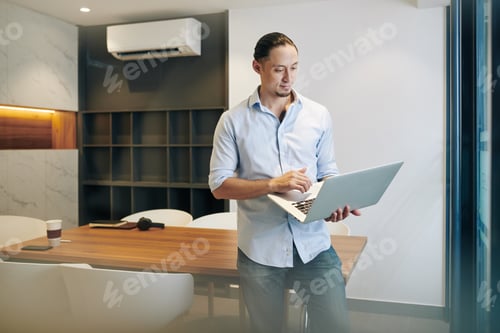 Preview: Man Using Laptop in Modern Corporate Office