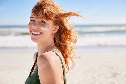 Preview: Smiling young woman sunbathing with sunscreen on cheek