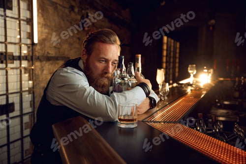 Preview: Portrait of sad mature man hugging bottle with alcoholic beverage