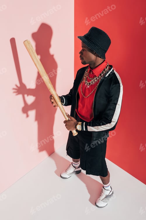 Preview: high angle view of stylish young african american man holding baseball bat in studio