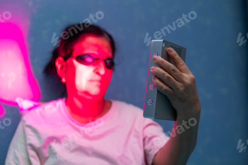 Preview: Closeup of woman doing the red light therapy session with handheld device