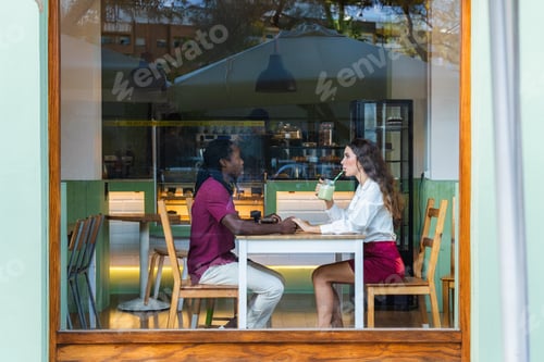 Preview: Multiracial couple holding hands having romantic date in cafe