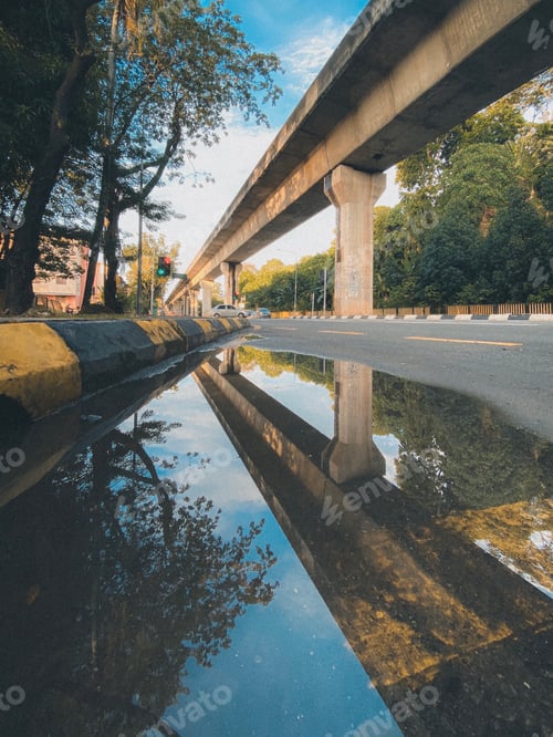 Preview: Cityscape Reflection in Puddle Under Elevated Train Track