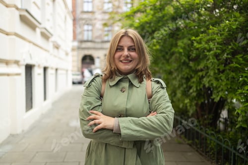 Preview: Portrait of a beautiful Caucasian female in a green coat, carrying a walking bag, smiling in a good