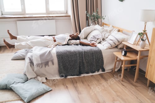 Preview: Happy black woman lying on bed and resting at home