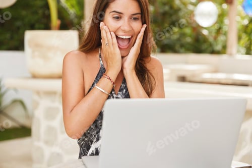 Preview: Glad overjoyed female happy to read positive news on internet webstore, looks joyfully into screen o
