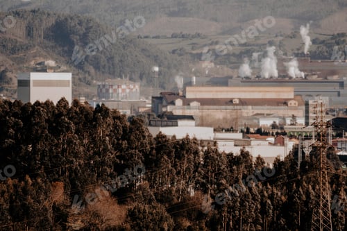 Preview: Aerial shot of industrial factories surrounded by hills with trees on the foreground