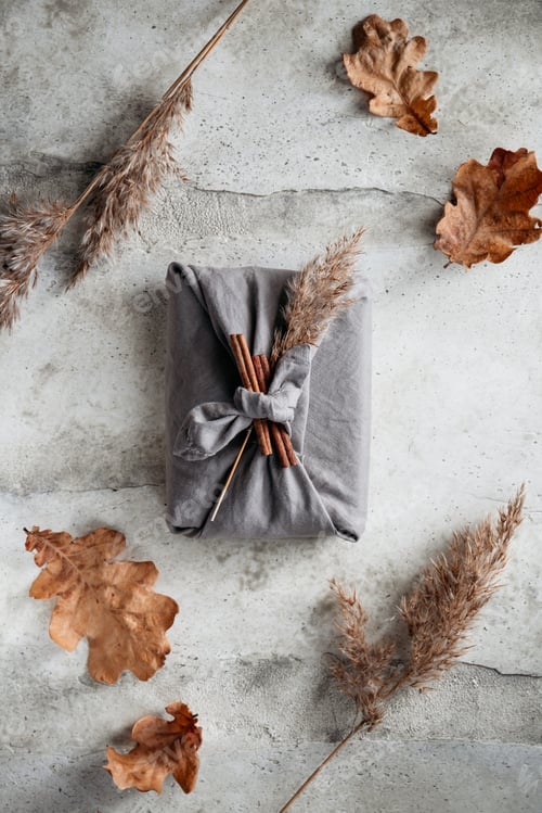Preview: Top view of wrapped gifts by linen fabric in furoshiki eco style with Autumn decor.