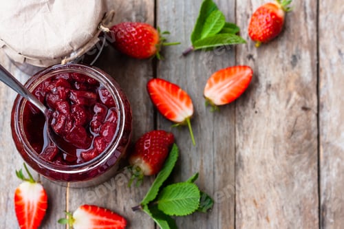 Preview: Strawberry jam in a glass jar with some fresh strawberry on wooden old rustic table.