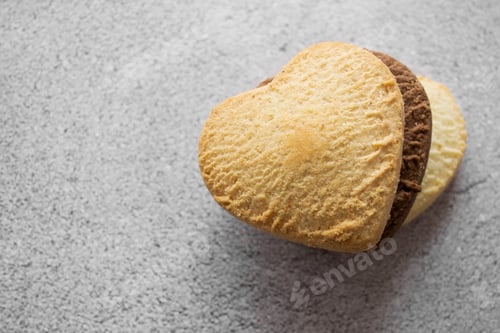 Preview: Close-up of three heart-shaped cookies: vanilla, chocolate, lemon. Gray background, copy space