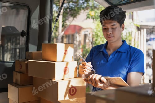 Preview: Asian young delivery man courier in uniform hold documents clipboard and box checking list parcel