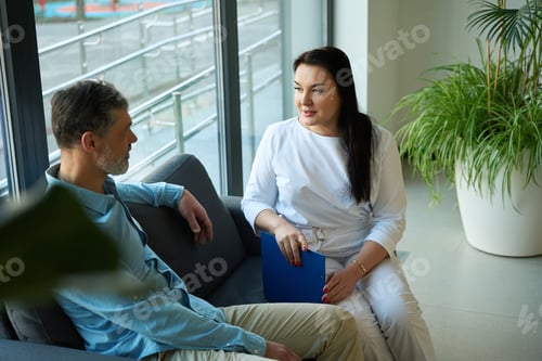 Preview: Patient with doctor sitting at reception surrounded by flowers