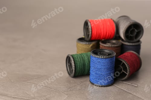 Preview: Set of color sewing threads on grey table, space for text