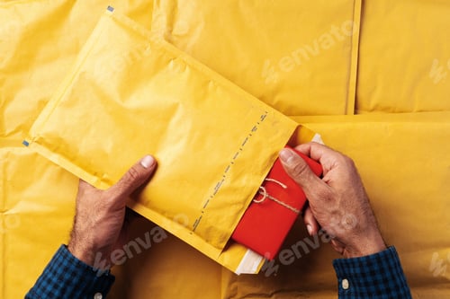 Preview: Male hands packing yellow bubble envelopes for shipping.