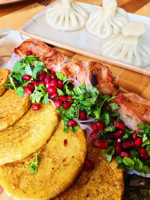 Preview: Shish kebab with juicy greens, pomegranate seeds and baked potatoes, khinkali. Traditional Georgian
