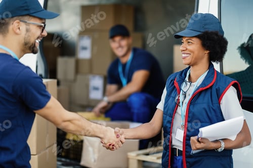 Preview: Two happy delivery workers shaking hands outdoors.
