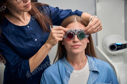Preview: Optometrist adjusting trial lenses on patients face