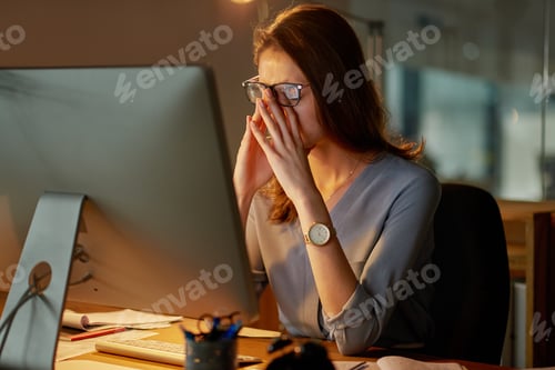 Preview: Shot of an attractive young businesswoman looking stressed while working late in the office