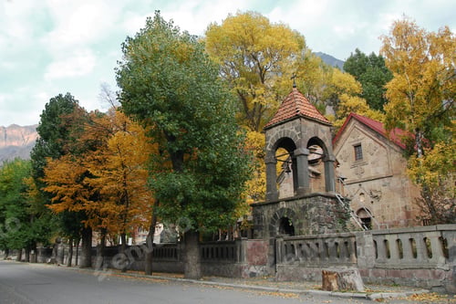 Preview: View on Medieval Orthodox Church with autumn trees on a background of mountains in cloudy weather.