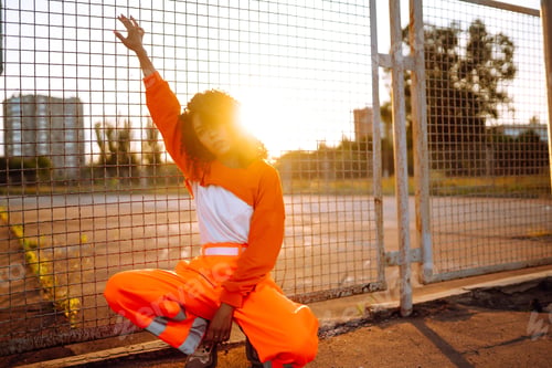 Preview: Young African American woman - dancer dancing in the street at sunset. Stylish woman with curly hair