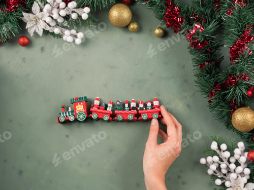 Preview: Christmas background with kids toy train and female hand holding it