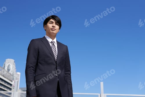 Preview: A Japanese male businessman stands in an office district.