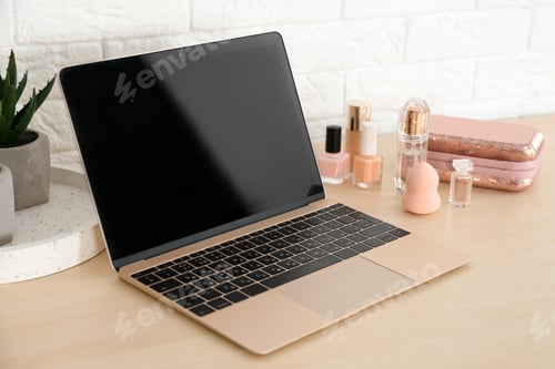 Preview: Stylish workplace with modern laptop and cosmetic products on table near brick wall. Beauty blogger