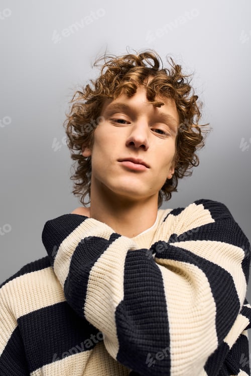 Preview: Stylish young man showcases fashion forward attitude with curly hair and unique sweater design
