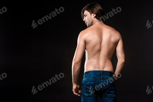 Preview: back view of young shirtless man in jeans looking away isolated on black