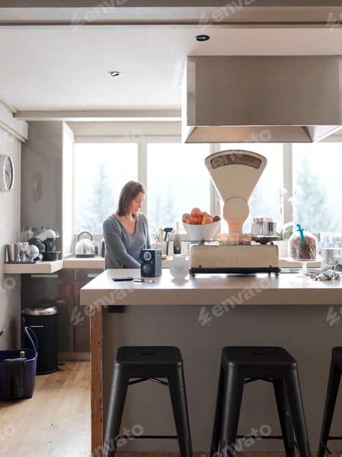Preview: Mature woman in kitchen, pensive expression
