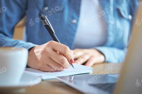 Preview: Woman writing some interesting information in notebook.