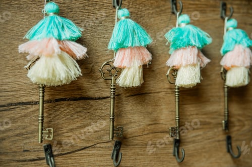 Preview: Colorful tassel keychains with vintage keys on wooden wall for boho and decorative concept