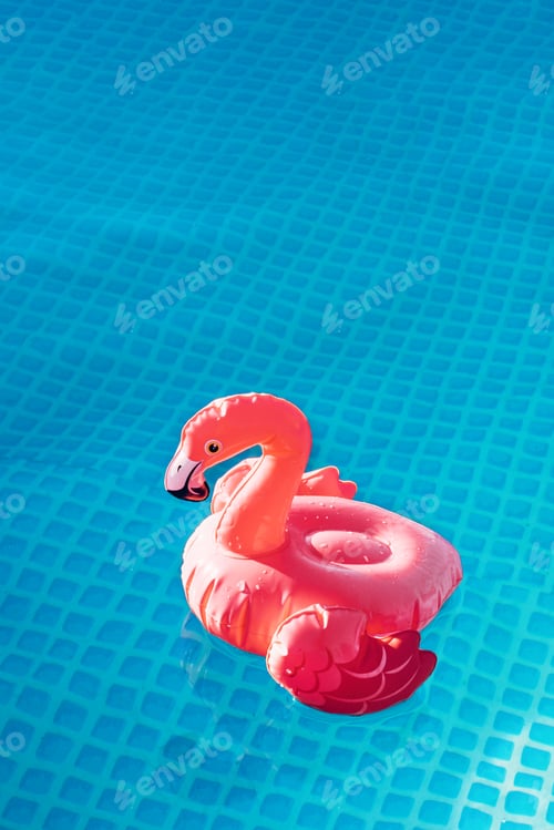 Preview: An inflatable pink flamingo toy floats on water of pool, alone, no one. Summer background