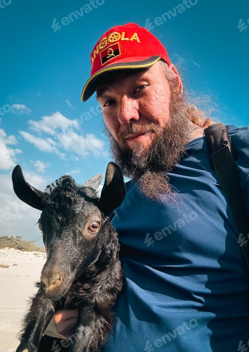 Preview: Tourist holding a goat during visit in Socotra island exploring unique wildlife and nature