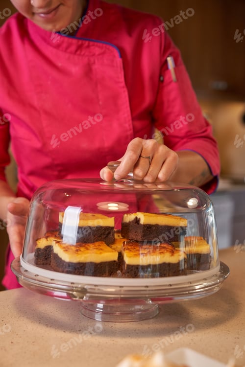 Preview: Crop woman serving sliced dessert on glass stand