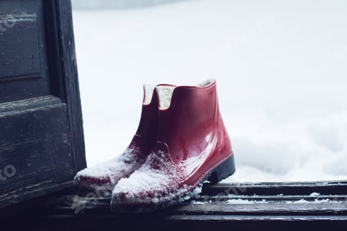 Preview: red rubber shoes covered in snow by the door
