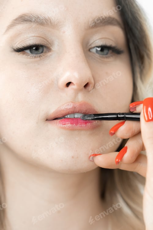 Preview: In a beauty salon, a young woman enjoys graceful lip makeup from a professional makeup artist. The