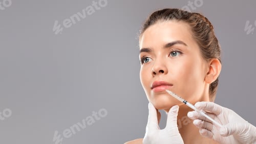 Preview: Young pretty woman getting lip filler over grey background
