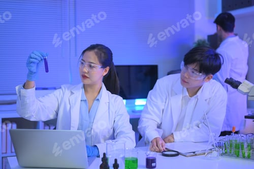 Preview: Two scientists review a purple liquid sample together in a modern laboratory