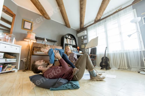 Preview: Happy young family playing on the floor at rustic room