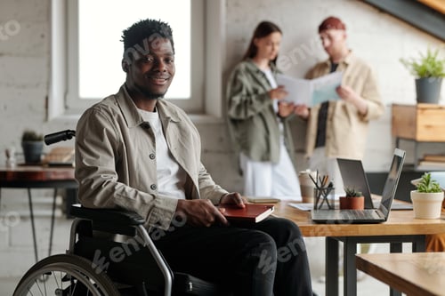 Preview: Happy young African American male broker with disability sitting in wheelchair