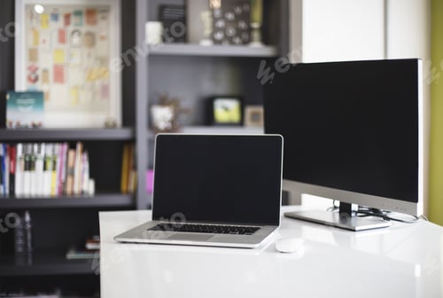 Preview: Shot of a laptop and a computer on a white desk in an office room