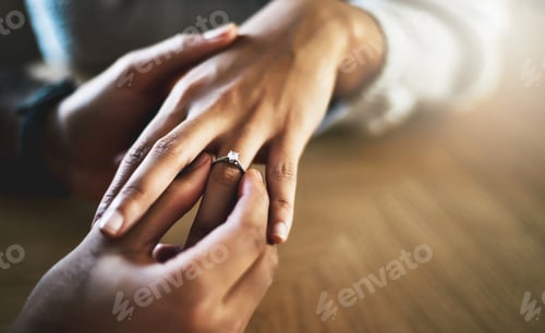 Preview: Cropped shot of a man putting an engagement ring onto his girlfriends finger