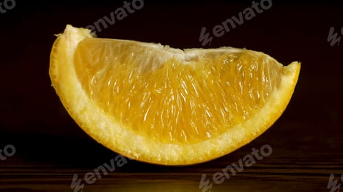 Preview: Juicy Fresh Fruit Orange Segments Against a Black Background. Fresh, juicy slice of orange rests on
