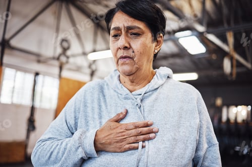 Preview: Senior woman with chest pain or injury in the gym after a intense workout or training. Healthcare,
