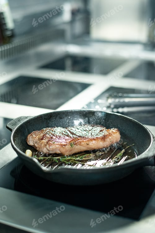 Preview: Hot roasted beef steak seasoned with fresh aromatic herbs on grill frying pan