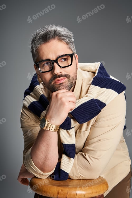 Preview: Stylish man in glasses showcases elegant fashion in modern studio setting