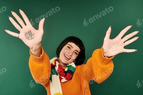 Preview: A cheerful young woman in a cozy sweater poses against a green backdrop