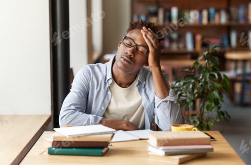 Preview: African American guy with books exhausted from studying or working at urban cafe