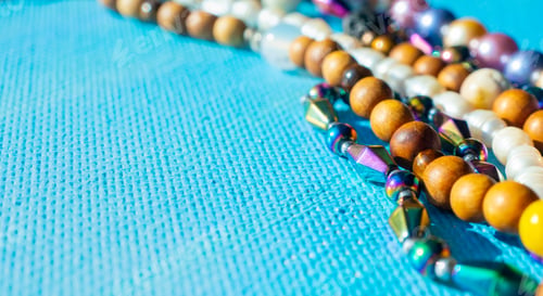 Preview: Heap of colored bright jewelry beads on a blue background. Different gems beads necklace.